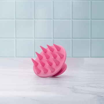 Pink silicone massager on a light blue tiled background